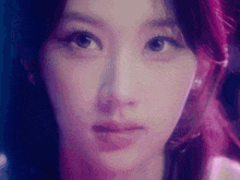 a close up of a woman 's face with a purple background and a purple light behind her .