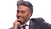 a man wearing a suit and tie is smiling with his hand on his chin
