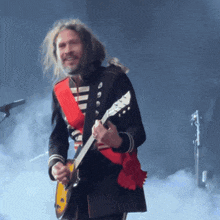 a man in a black and white uniform is playing a guitar on stage