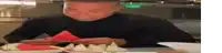 a man is sitting at a table eating a watermelon slice .