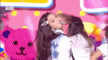 a girl with a microphone on her head is dancing in front of a pink teddy bear .