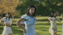 a woman in a blue dress is dancing in a field with other women
