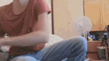 a person sitting in front of a fan with a red shirt that says ' i love you '