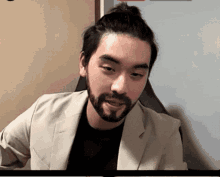 a man with a beard wearing a white jacket and black shirt