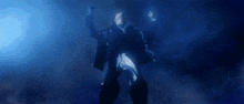 a man in a black jacket is standing in the dark with his arms outstretched and holding a gun .