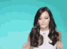 a woman in a white dress is pointing at something with a cross in her hair .