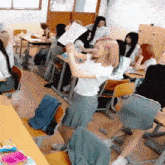 a girl with pink hair holds up a piece of paper in front of a group of students