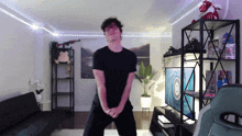 a man in a black shirt is dancing in a living room with a target on the wall