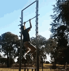 a man is doing a pull up on a bar in a park