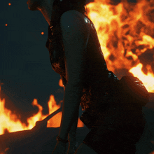 a woman is standing in front of a fire in the dark