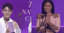 a man and a woman are standing next to each other on a stage . the woman is holding a microphone .
