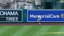 a baseball player is catching a ball in front of a memorial care sign