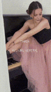 a woman in a pink skirt is sitting at a piano with the name tanja helsinki central written on the bottom