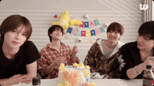a group of young men sitting around a table with a cake that says os