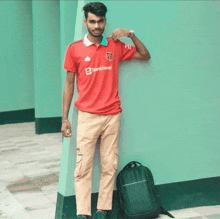 a man wearing a red teamviewer shirt stands next to a green wall