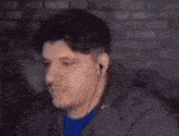 a blurry picture of a man in a blue shirt standing in front of a brick wall with his eyes closed .