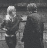 two men standing next to each other holding hands and looking at each other