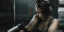 a woman wearing headphones is holding a gun with the ign logo visible