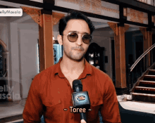 a man wearing sunglasses is holding a microphone and says toree