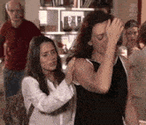 two women are standing next to each other and one is holding the other 's head