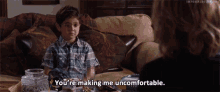 a young boy is sitting on a couch talking to a woman who says " you 're making me uncomfortable "