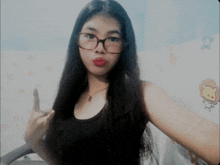 a girl wearing glasses and a black tank top is taking a selfie