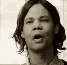 a man with long hair is talking with his mouth open