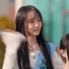 a girl with long hair is wearing a white shirt and a blue vest with a button that says " i love you "