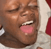 a close up of a child 's face with his mouth open and his tongue hanging out .