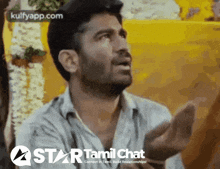 a man is talking in front of a yellow wall with the words star tamil chat on the bottom