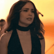 a woman in a black dress with a choker around her neck looks at the camera