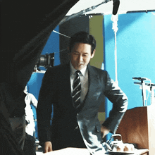 a man in a suit and tie standing in front of a blue wall