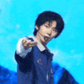 a young man wearing a microphone is pointing at the camera .