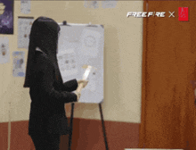 a woman stands in front of a white board with free fire written on it