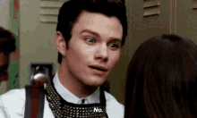 a man in a suit and tie is talking to a woman in a locker room and says no .