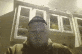 a man with a beard and a hat is standing in front of a kitchen cabinet