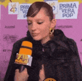 a woman is holding a microphone in front of a sign that says primavera vera pop