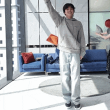a person standing in front of a blue couch with their arms outstretched