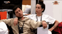 a man and a woman are sitting on a couch in front of a tv screen that says tvreality