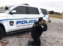 a man is kneeling in front of a police car