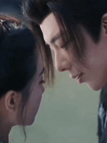 a man and a woman are touching their foreheads and looking at each other .