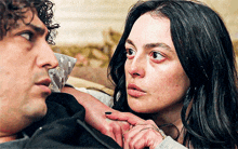 a man and a woman are laying on a couch and the woman has a ring on her finger