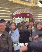 a crowd of people are gathered in front of a building with chinese writing on it