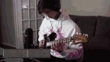 a man wearing headphones plays an ibanez guitar in front of a microphone