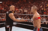 two wrestlers in a ring with one wearing a sign that says let 's all