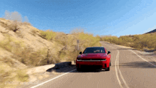 a red car is driving down a road with motorweek.org written on the bottom right