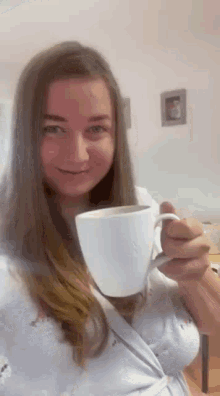 a woman in a robe is holding a cup of coffee .