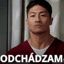 a man in a maroon scrub top is looking at the camera with the words " odchadzam " behind him