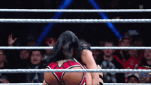 a woman is wrestling another woman in a wrestling ring with a crowd watching .