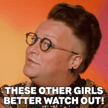 a man wearing glasses and earrings says these other girls better watch out